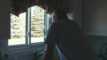 man looking out a window in his kitchen 