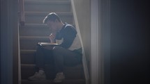 a man sitting on steps reading a Bible and praying to God 