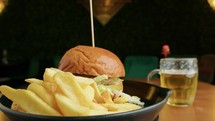 Gourmet Burger Dish Served With Fries And A Fresh Beer