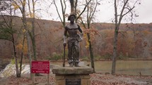 Statue of unemployed members CCC in Devil's Den State Park Cascade Waterfalls and River Lake during Autumn Fall Foliage Arkansas USA