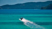 Small boat drives on crystal clear blue water to exotic island. Boat trip. Long Tail Boat. 