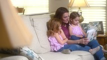 mother and daughters reading a children's Bible together 