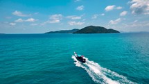 Wooden boat in turquoise sea, movement on blue water. Trip boat with tourists sailing on clean blue sea surface. A long-tailed Thai boat sails among the islands, touristic excursion ride. Aerial. 