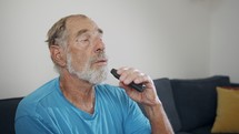 Man with Parkinson's disease using medical Cannabis in vaporizer to stop shaking