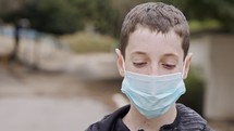 Coronavirus pandemic close up on boy face wearing face mask to avoid contagion