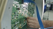 Close up on worker hand connecting wires to a large circuit board