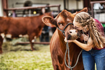 Girl kissing her heifer at a county fair competition. 