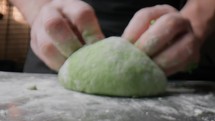 Hands Of A Chef Vigorously Knead Green Flour For Spaghetti Pasta