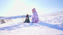 Children playing in the snow. Little boy and old sister outside in the winter park in winter throwing snow. Boy and a girl are walking in the snow in a winter time at sun. Family winter holidays.