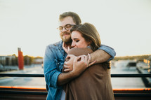 couple standing on a bridge hugging 