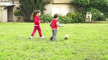 Two young kids playing with a ball in slow motion outdoors