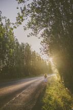 Woman walking down a rural road under sunlight
