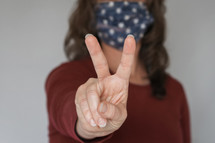 woman with a peace sign wearing a cloth mask