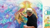 Man painting a mural of God creating the universe.
