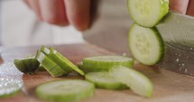 Macro shot of a chef knife slicing a cucumber