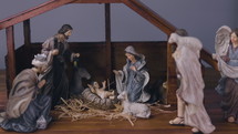 Jesus Christ Nativity scene with figurines in stable and light particles. Jesus Christ birth in a manger with Mary and Joseph. Christmas scene. Dolly shot 4k