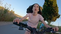 POV of a young girl enjoying a bicycle ride on the rural countryside.