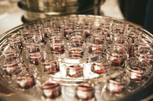 A communion tray filled with communion cups of wine.