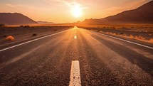 Black Asphalt Road And White Dividing Lines. In a desert at sunset light.
