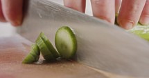 Macro shot of a chef knife slicing a cucumber