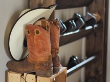 cowboy boots and cowboy hat on a shoe rack 