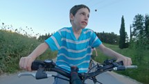 POV of a young boy enjoying a bicycle ride on the rural countryside.