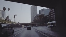 Traveling through downtown Los Angeles passing tall buildings and overpasses.