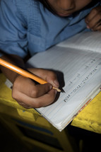 Child writing on notebook paper in a classroom in Honduras
