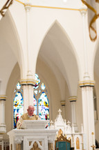 Priest speaking at the altar in a cathedral.