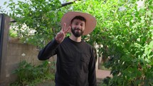 Happy Man With Round Hat Makes Victory Sign With His Hand