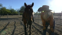 A mature woman cowgirl talking to her horse before a ride