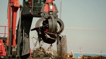 Large grapple claw picking up and moving scrap metal.