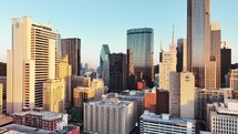 Aerial video of downtown Dallas, Texas during sunrise with highways, traffic and skyscraper buildings in the background.