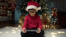 Child playing videogames under the Christmas tree 
