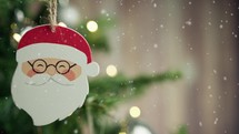 Santa Claus face as decoration on a Christmas tree with snow falling 