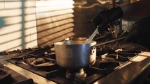 Professional chef cooking in a pot with sunlight from the window
