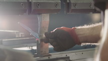Factory worker bending metal parts with a machine