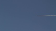 A jet airline with contrails high overhead