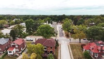 Drone video circling an old brick catholic or cathedral church inside a neighborhood.