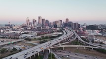 Aerial video of downtown Dallas, Texas during sunrise with highways, traffic and skyscraper buildings in the background.