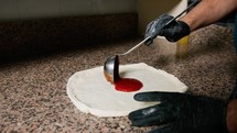 Pizza Chef Adding The Tomato Sauce On Dough Before Baking It