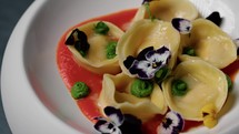 A Gourmet Dish With Stuffed Ravioli And Colorful Creams