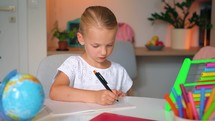 Child Kid Girl doing her homework art a desk. School girl whrites in a notebook. Education concept. Cute smart school child girl writing doing homework.	
