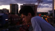 A pensive young man in the city at dusk