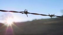 Sunrise over a barbed wire fence.