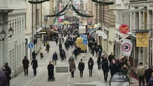 pedestrians walking down a crowded downtown street at Christmas time 