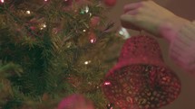 Christmas Tree Shoot - Woman hangs bell ornament on tree.