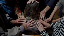 Christian friends laying hands and praying over a woman in need