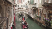 The atmosphere of narrow canals in the city of Venice, with many bridges and small boats parked.