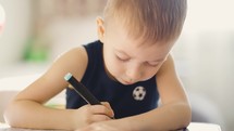 Drawing. Little boy with pencil coloring at home. Child draws at the table. Psychology of the child's personality. Help gaining confidence. Creativity and education concept.
